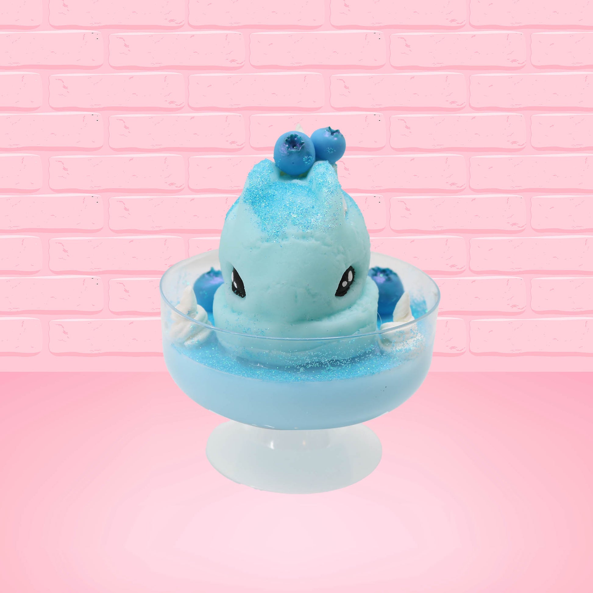 Cute kawaii Blue Berry Cotton Candy ice cream sundae with blue berries and swirls of whipped cream in the dish, while covered with blue glitter.  The bunny has two blue berries on the top near the swirl of whipped cream on the back. This view is from the front.