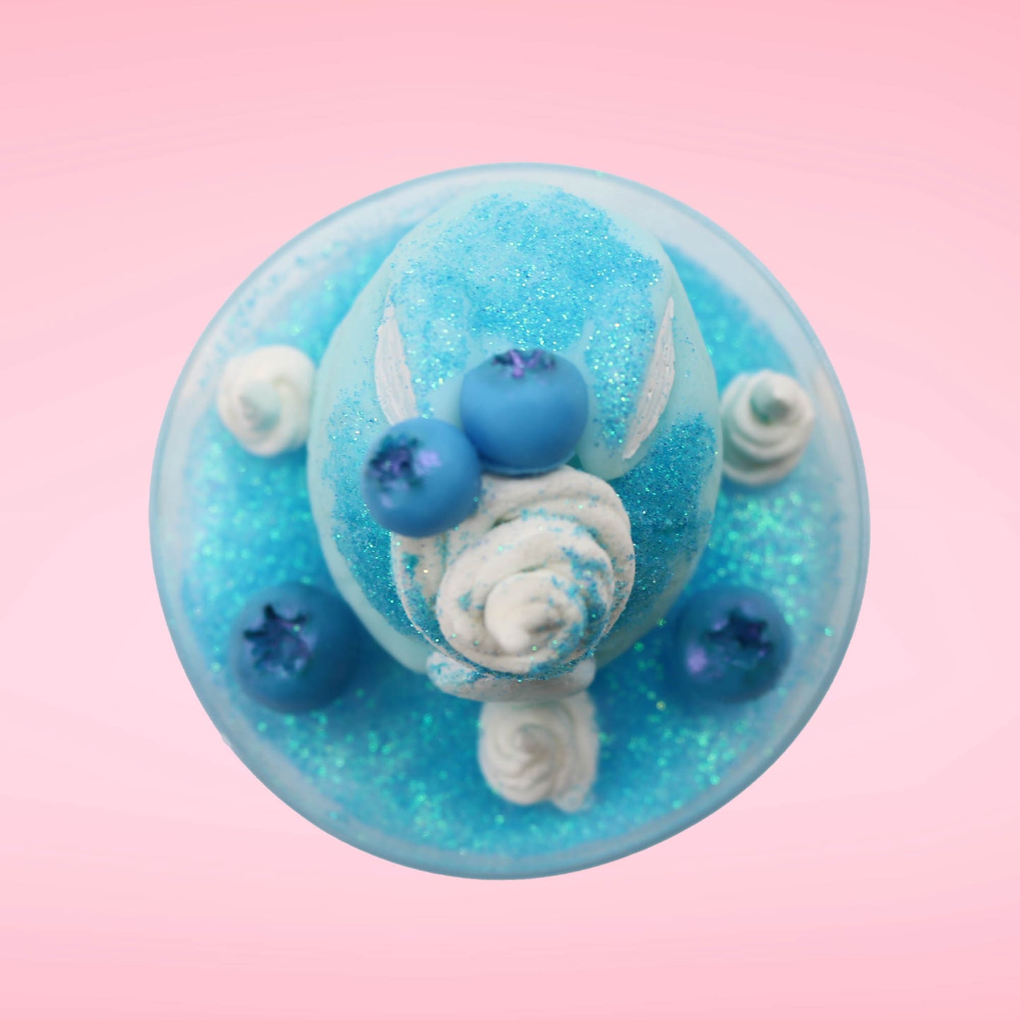 Cute kawaii Blue Berry Cotton Candy ice cream sundae with blue berries and swirls of whipped cream in the dish, while covered with blue glitter.  The bunny has two blue berries on the top near the swirl of whipped cream on the back. This view is from the top.
