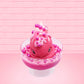 Cute kawaii bunny Bubbles pink ice cream sundae with light pink drizzle, pink and hot pink metallic spheres inside the dish. The bunny’s top is covered with the pink and hot pink spheres as well as a swirl of whipped cream. This view is from the front.