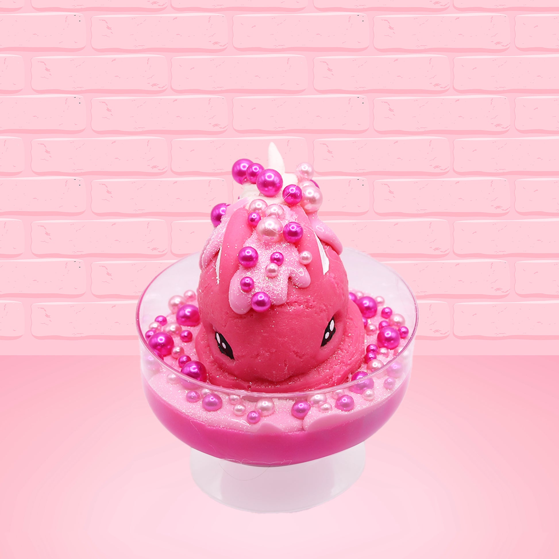 Cute kawaii bunny Bubbles pink ice cream sundae with light pink drizzle, pink and hot pink metallic spheres inside the dish. The bunny’s top is covered with the pink and hot pink spheres as well as a swirl of whipped cream. This view is from the front.