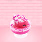 Cute kawaii bunny Bubbles pink ice cream sundae with light pink drizzle, pink and hot pink metallic spheres inside the dish. The bunny’s top is covered with the pink and hot pink spheres as well as a swirl of whipped cream. This view is from the side.