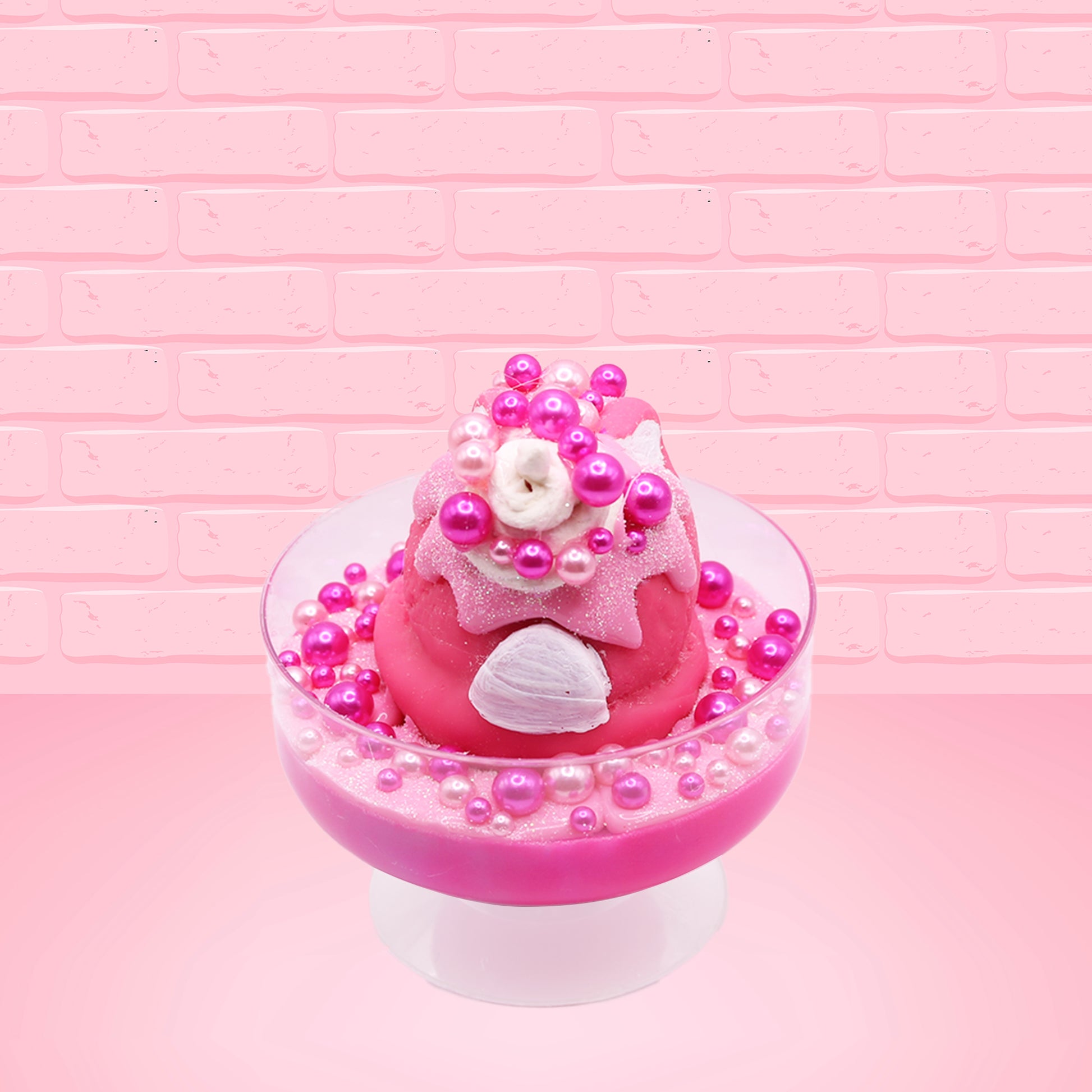 Cute kawaii bunny Bubbles pink ice cream sundae with light pink drizzle, pink and hot pink metallic spheres inside the dish. The bunny’s top is covered with the pink and hot pink spheres as well as a swirl of whipped cream. This view is from the back. 