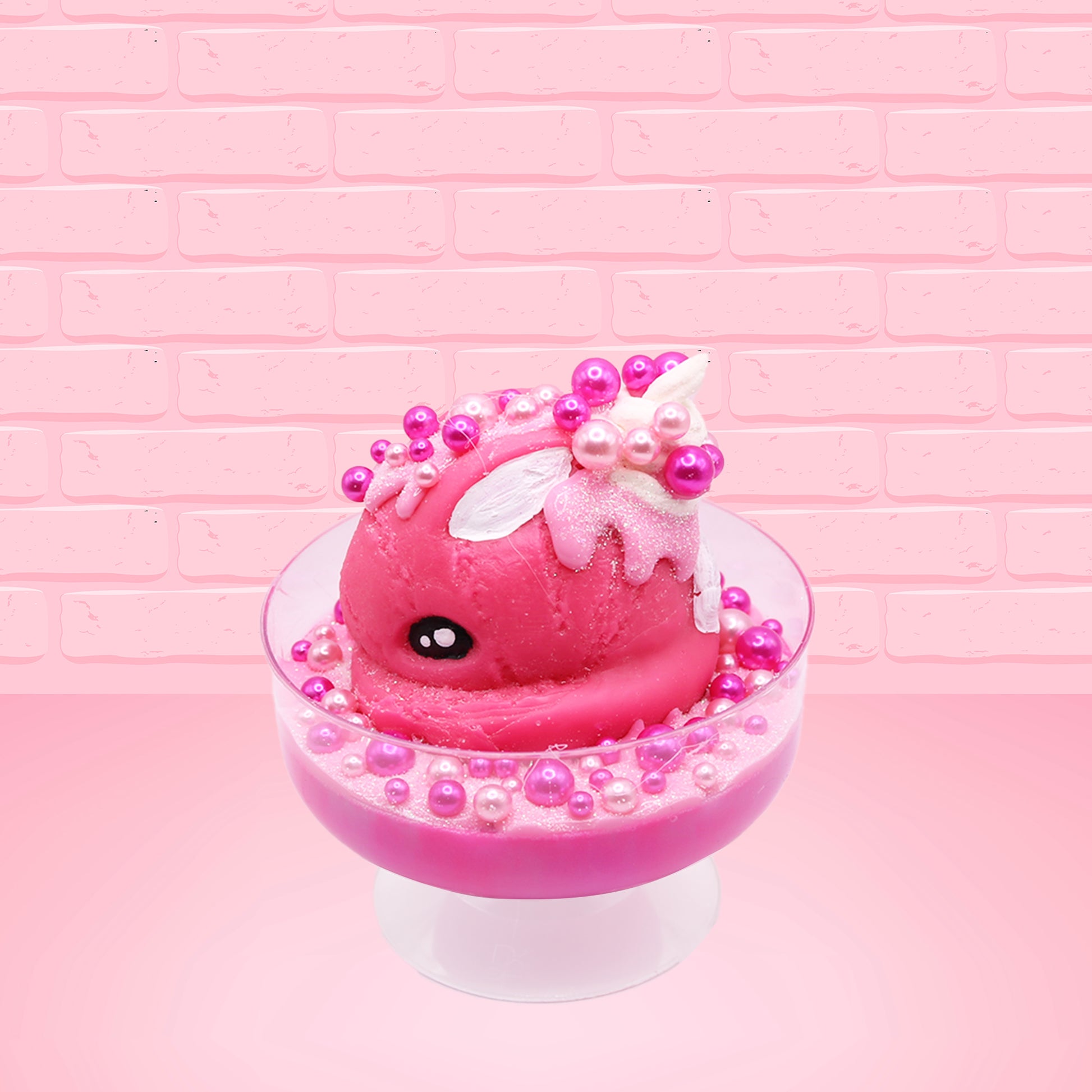 Cute kawaii bunny Bubbles pink ice cream sundae with light pink drizzle, pink and hot pink metallic spheres inside the dish. The bunny’s top is covered with the pink and hot pink spheres as well as a swirl of whipped cream. This view is from the other side.