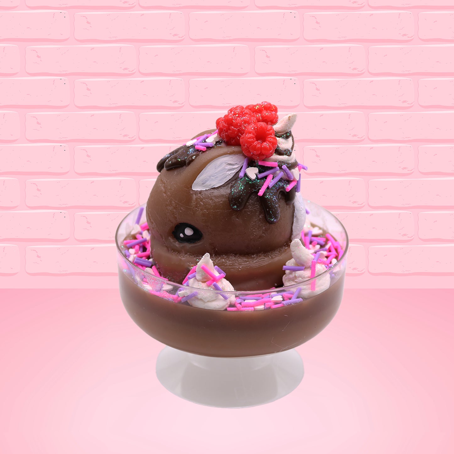 Cute kawaii bunny Chocolate Rush brown ice cream sundae with pink and purple sprinkles with swirls of whipped cream in the dish. The bunny has raspberries, chocolate glittery drizzle and sprinkles on top near the whipped cream swirl. This view is from the other side.