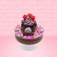 Cute kawaii bunny Chocolate Rush brown ice cream sundae with pink and purple sprinkles with swirls of whipped cream in the dish. The bunny has raspberries, chocolate glittery drizzle and sprinkles on top near the whipped cream swirl. This is from the back.