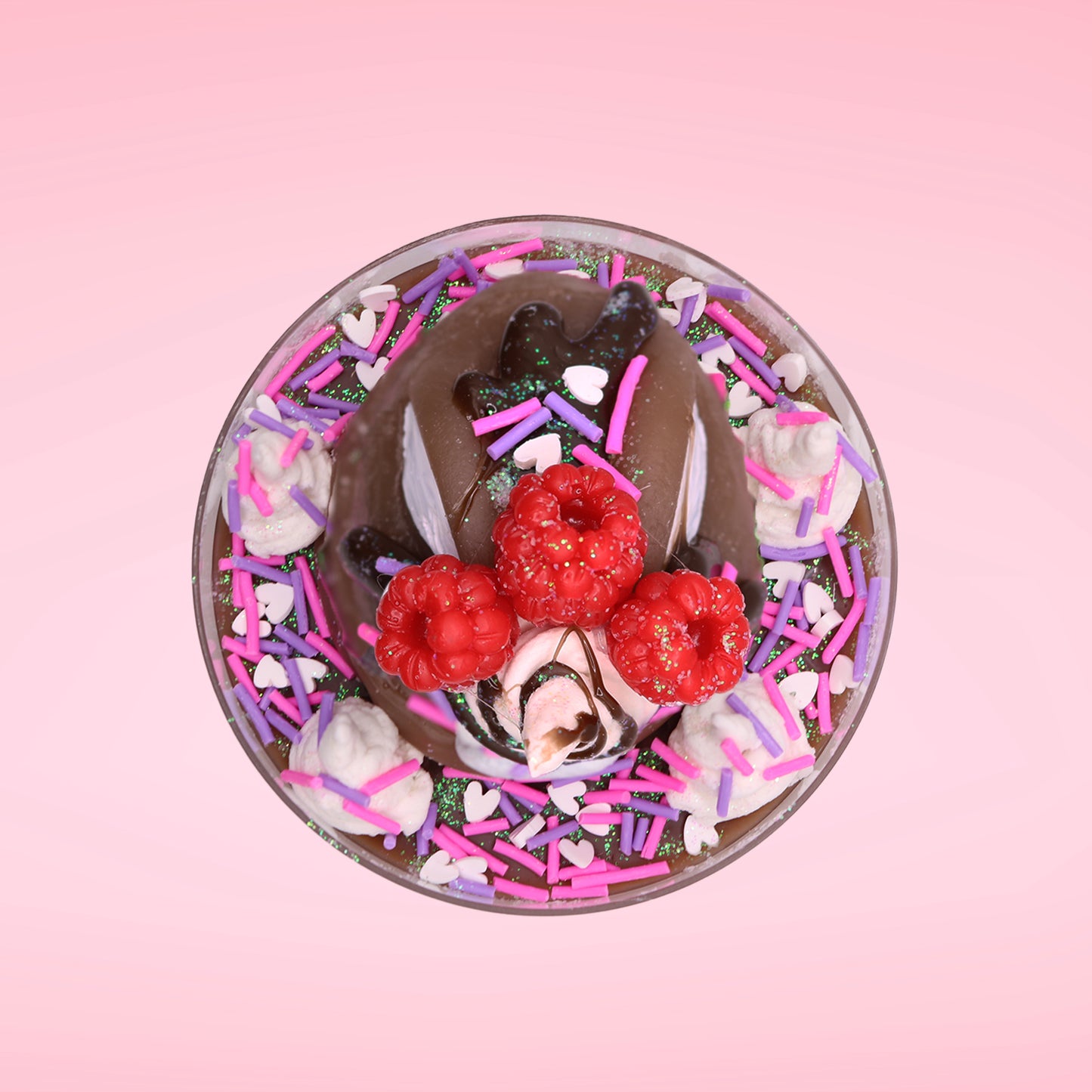 Cute kawaii bunny Chocolate Rush brown ice cream sundae with pink and purple sprinkles with swirls of whipped cream in the dish. The bunny has raspberries, chocolate glittery drizzle and sprinkles on top near the whipped cream swirl. This view is from the top.