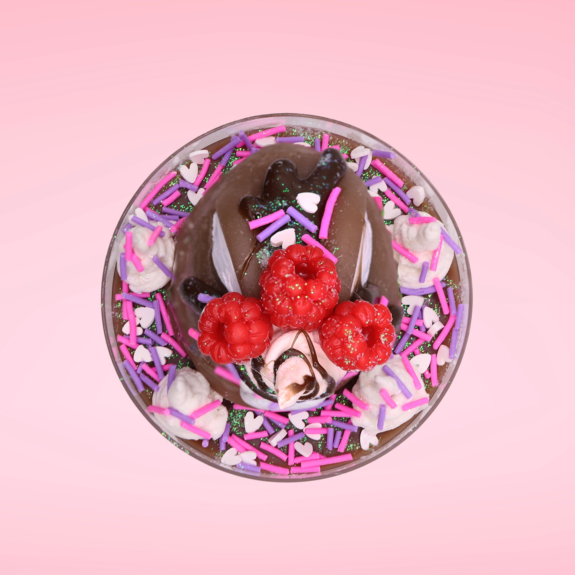 Cute kawaii bunny Chocolate Rush brown ice cream sundae with pink and purple sprinkles with swirls of whipped cream in the dish. The bunny has raspberries, chocolate glittery drizzle and sprinkles on top near the whipped cream swirl. This view is from the top.