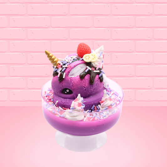 Cute kawaii unicorn bunny Coco Dazzle Star purple ice cream with pink, purple and white sprinkles with swirls of whipped cream in the dish. The unicorn bunny has a strawberry and banana slices with chocolate drizzle and sprinkles near the whipped cream swirl. This view is from the side.