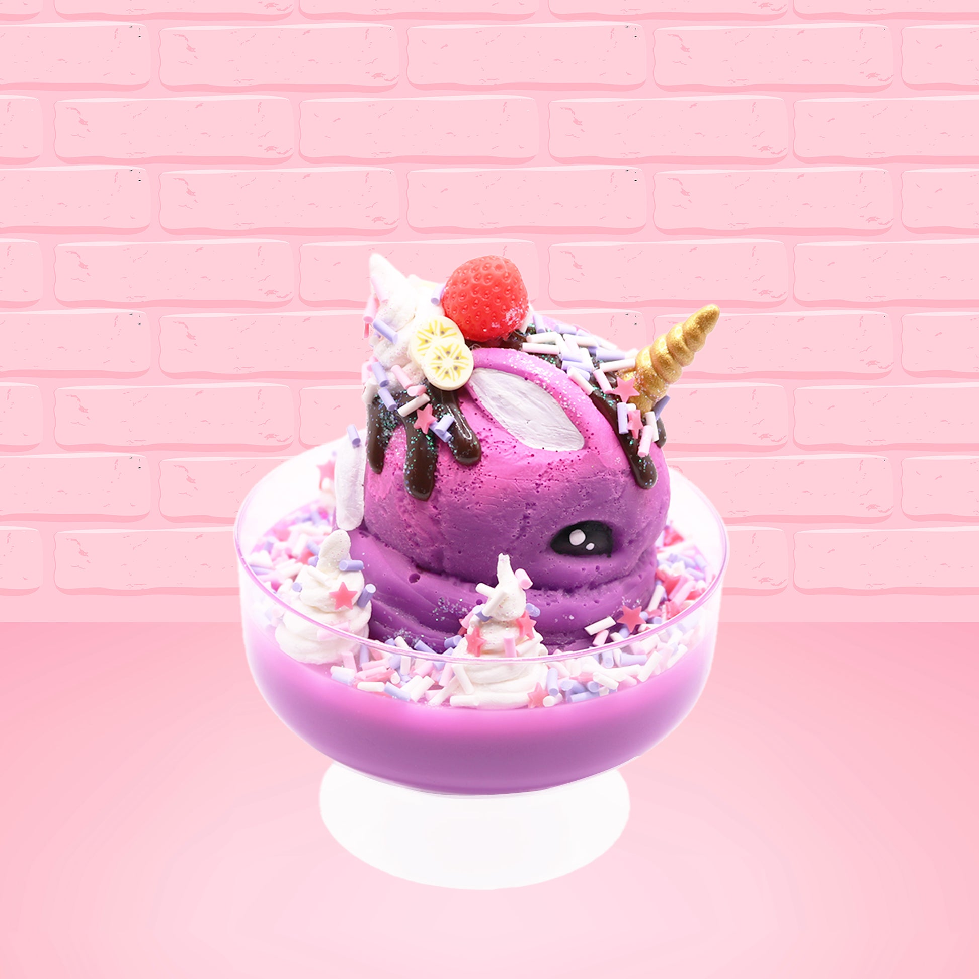 Cute kawaii unicorn bunny Coco Dazzle Star purple ice cream with pink, purple and white sprinkles with swirls of whipped cream in the dish. The unicorn bunny has a strawberry and banana slices with chocolate drizzle and sprinkles near the whipped cream swirl. This view is from the other side.