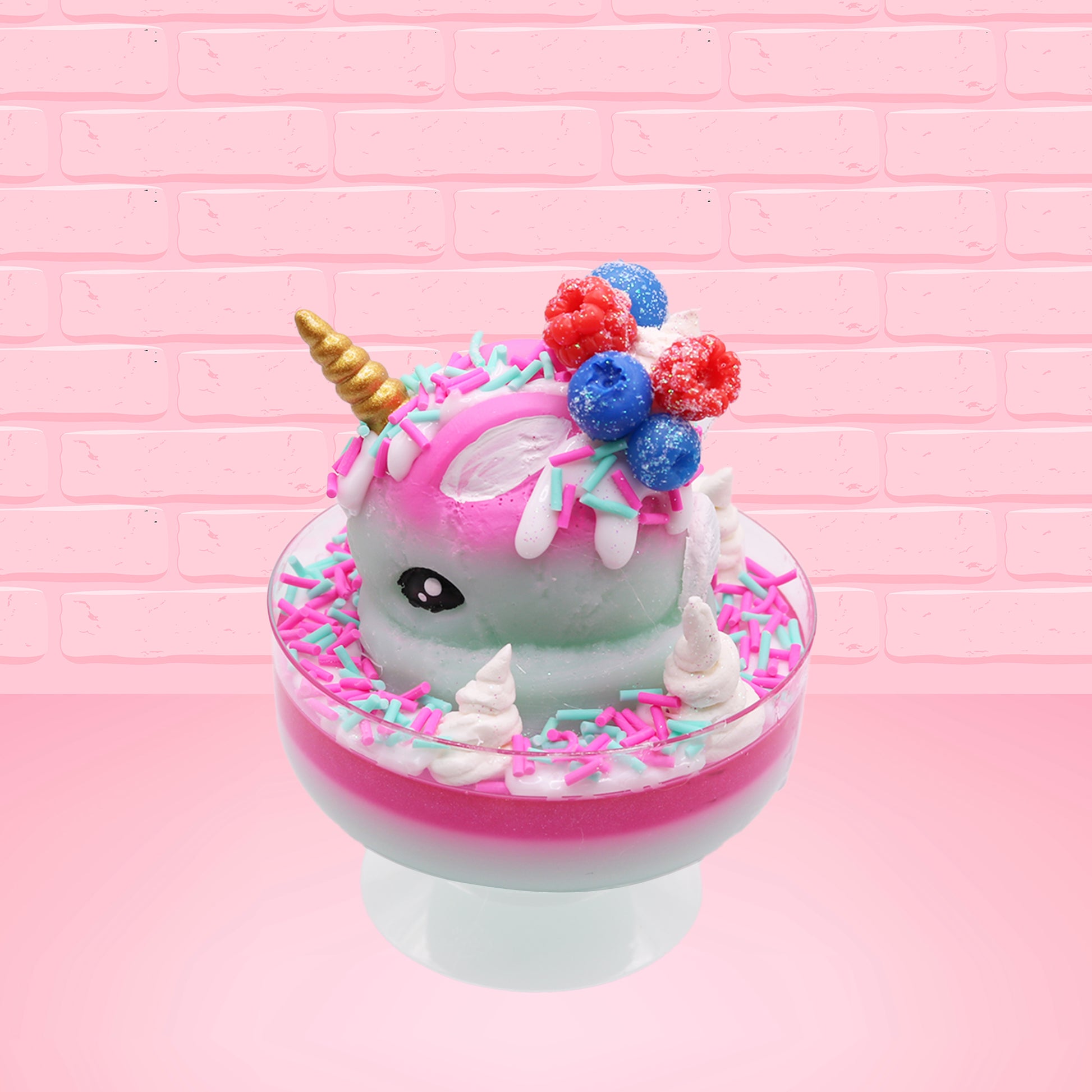 Cute kawaii unicorn bunny Irresistible Sugary Berry light blue and pink sundae with light blue and pink sprinkles with whipped cream swirls in the dish.  The unicorn bunny has blue berries and red raspberries on top near the whipped cream swirl with white drizzle coming down. This view is from the other side.