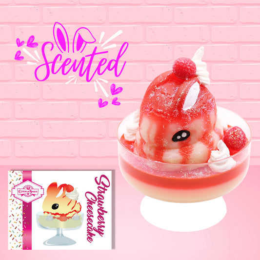 Cute kawaii bunny new strawberry cheesecake white ice cream with red translucent glaze, strawberries, and swirls of whipped cream in the dish. The bunny has red glittery glaze dripping over the head with a strawberry and a swirl of whipped cream on top. The character card front is shown, with the word scented.