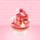 Cute kawaii bunny new strawberry cheesecake white ice cream with red translucent glaze, strawberries, and swirls of whipped cream in the dish. The bunny has red glittery glaze dripping over the head with a strawberry and a swirl of whipped cream on top. This view is from the other side.