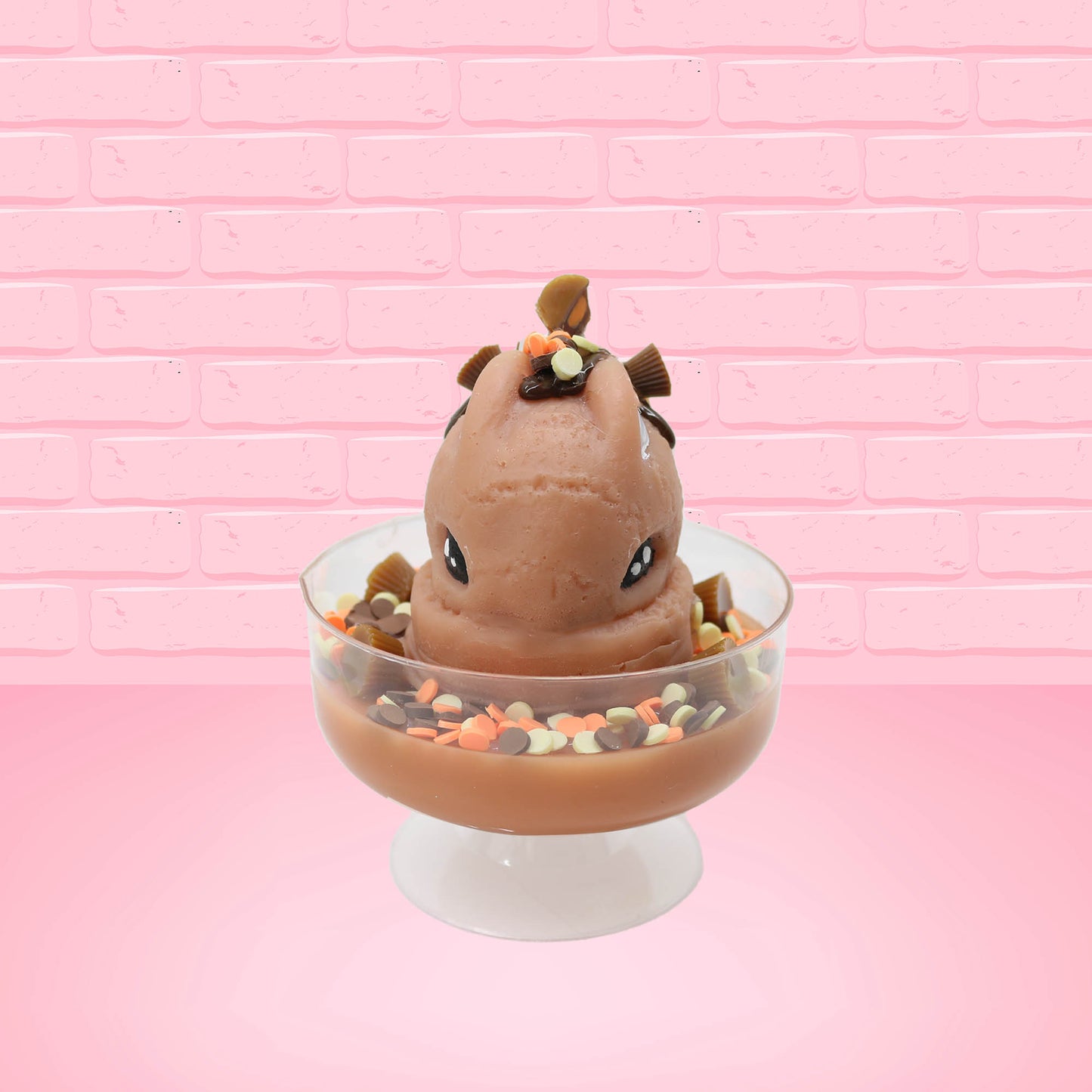 Cute kawaii peanut chocolate cup resin ice cream sundae with orange and white sprinkles in the dish. Chocolate drizzle and cups are on the top of the resin ice cream bunny, and a swirl whipped cream on top from the front.