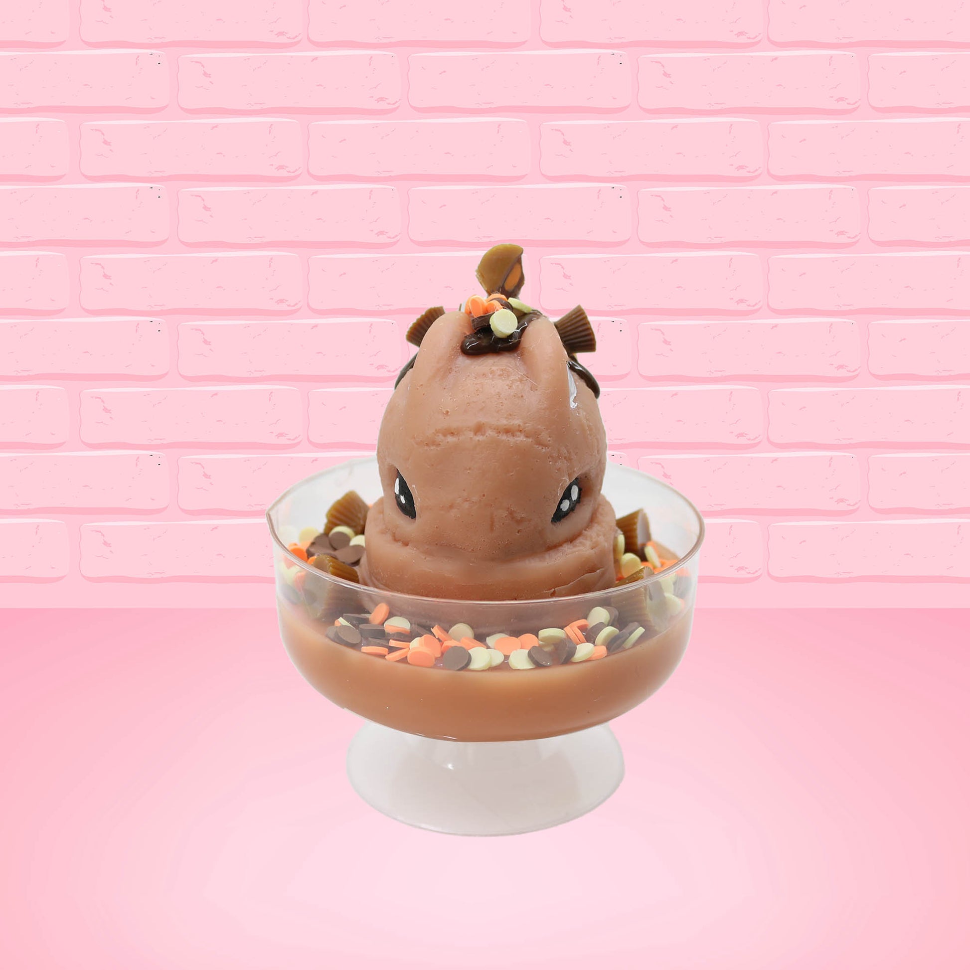 Cute kawaii peanut chocolate cup resin ice cream sundae with orange and white sprinkles in the dish. Chocolate drizzle and cups are on the top of the resin ice cream bunny, and a swirl whipped cream on top from the front.