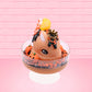 Cute kawaii Pumpkin King Bunny orange ice cream sundae with black glaze, orange sprinkles and pumpkin faces in the dish.  The bunny has a golden crown and orange slice on top next to the swirl of whipped cream. This view is from the front at a slight angle.