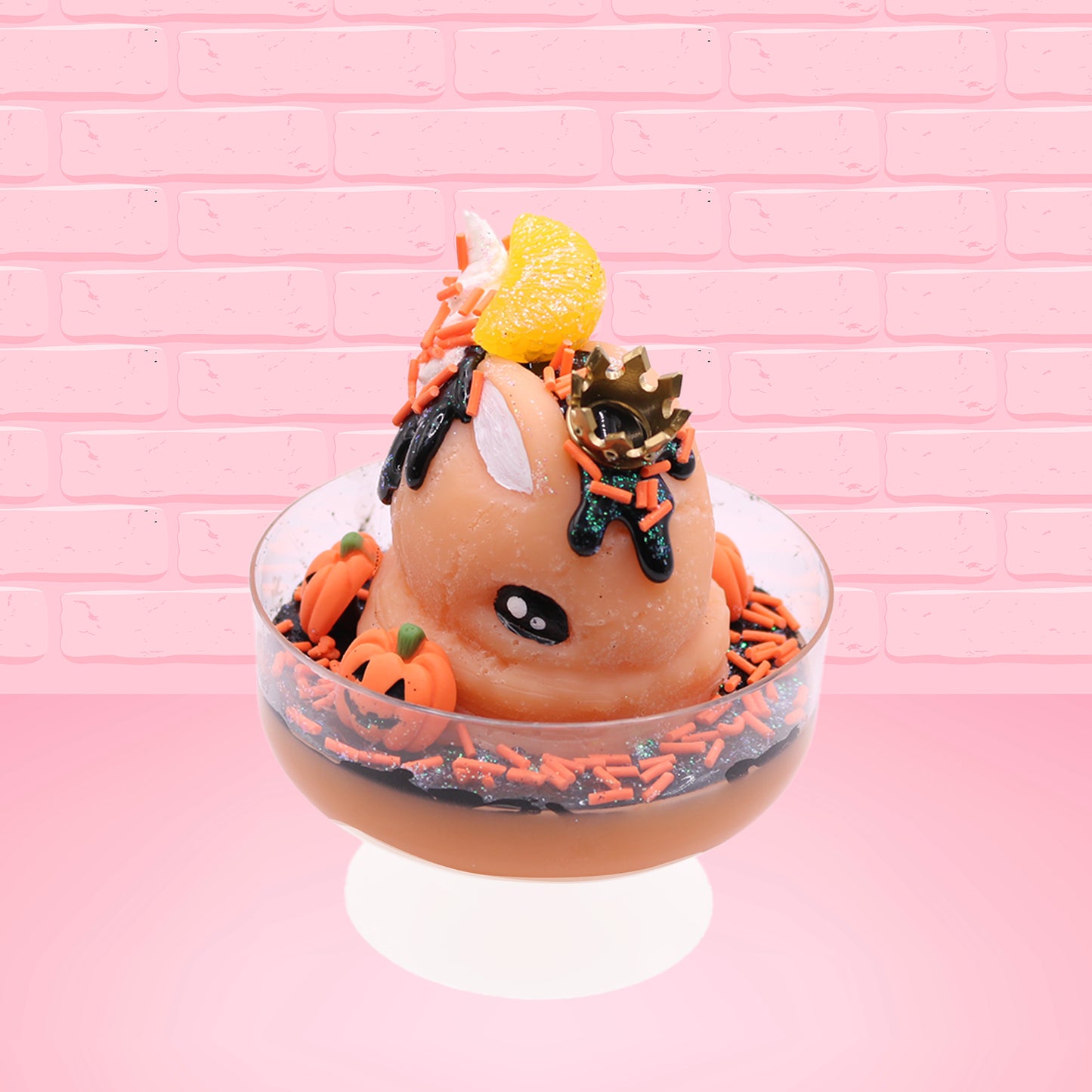 Cute kawaii Pumpkin King Bunny orange ice cream sundae with black glaze, orange sprinkles and pumpkin faces in the dish.  The bunny has a golden crown and orange slice on top next to the swirl of whipped cream. This view is from the front at a slight angle.