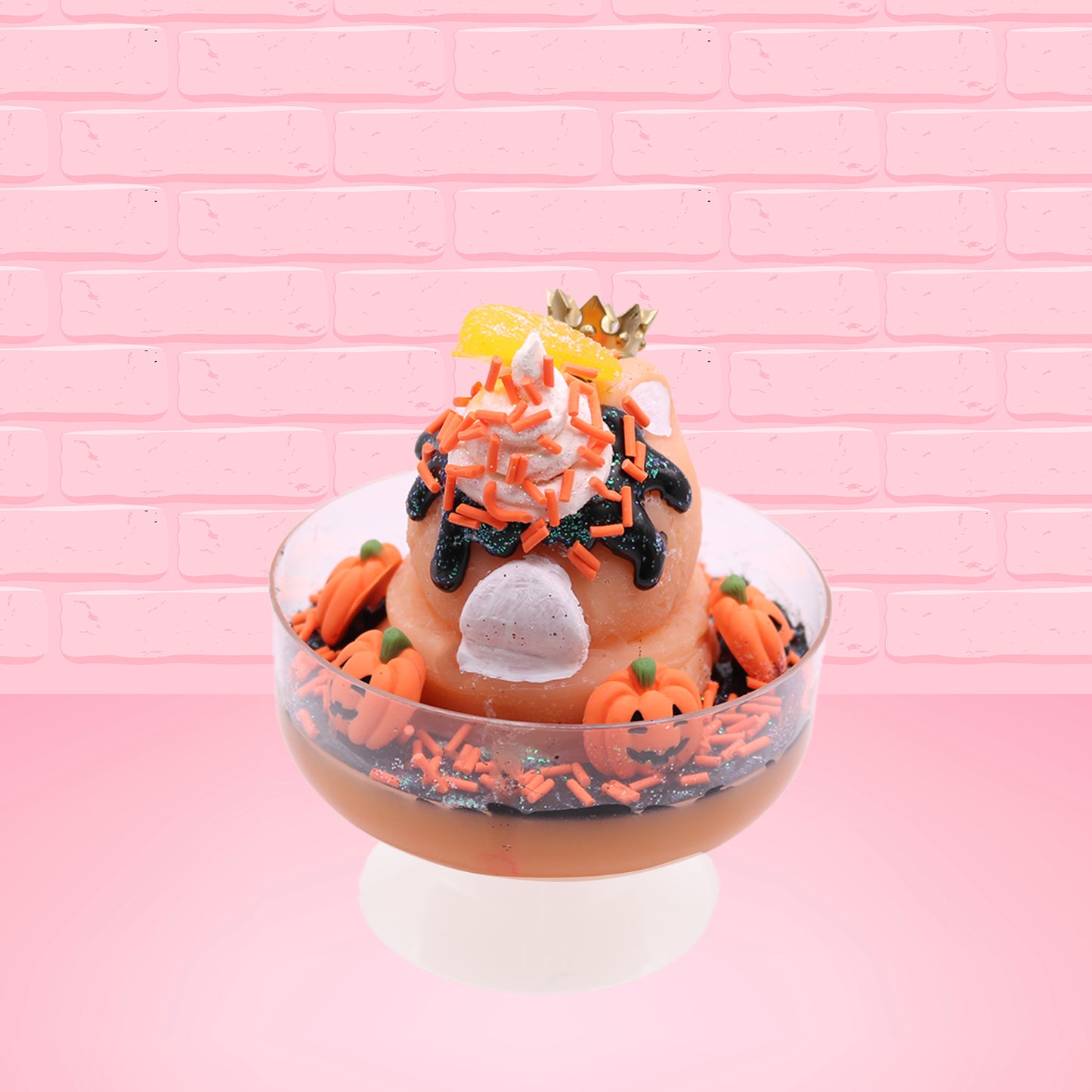 Cute kawaii Pumpkin King Bunny orange ice cream sundae with black glaze, orange sprinkles and pumpkin faces in the dish.  The bunny has a golden crown and orange slice on top next to the swirl of whipped cream. This view is from the back.