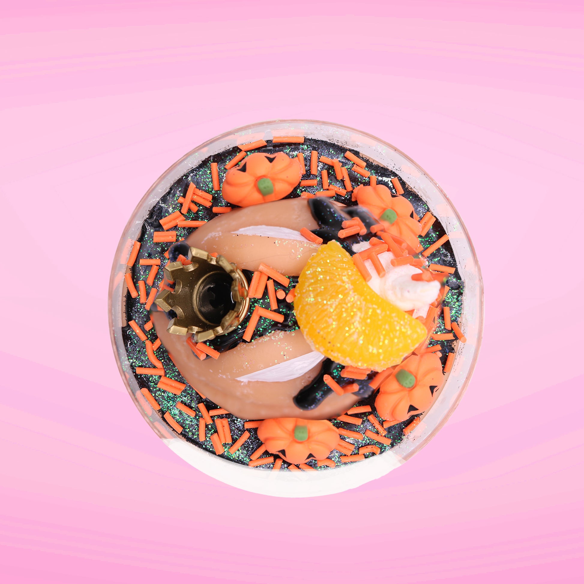 Cute kawaii Pumpkin King Bunny orange ice cream sundae with black glaze, orange sprinkles and pumpkin faces in the dish.  The bunny has a golden crown and orange slice on top next to the swirl of whipped cream. This view is from the top.