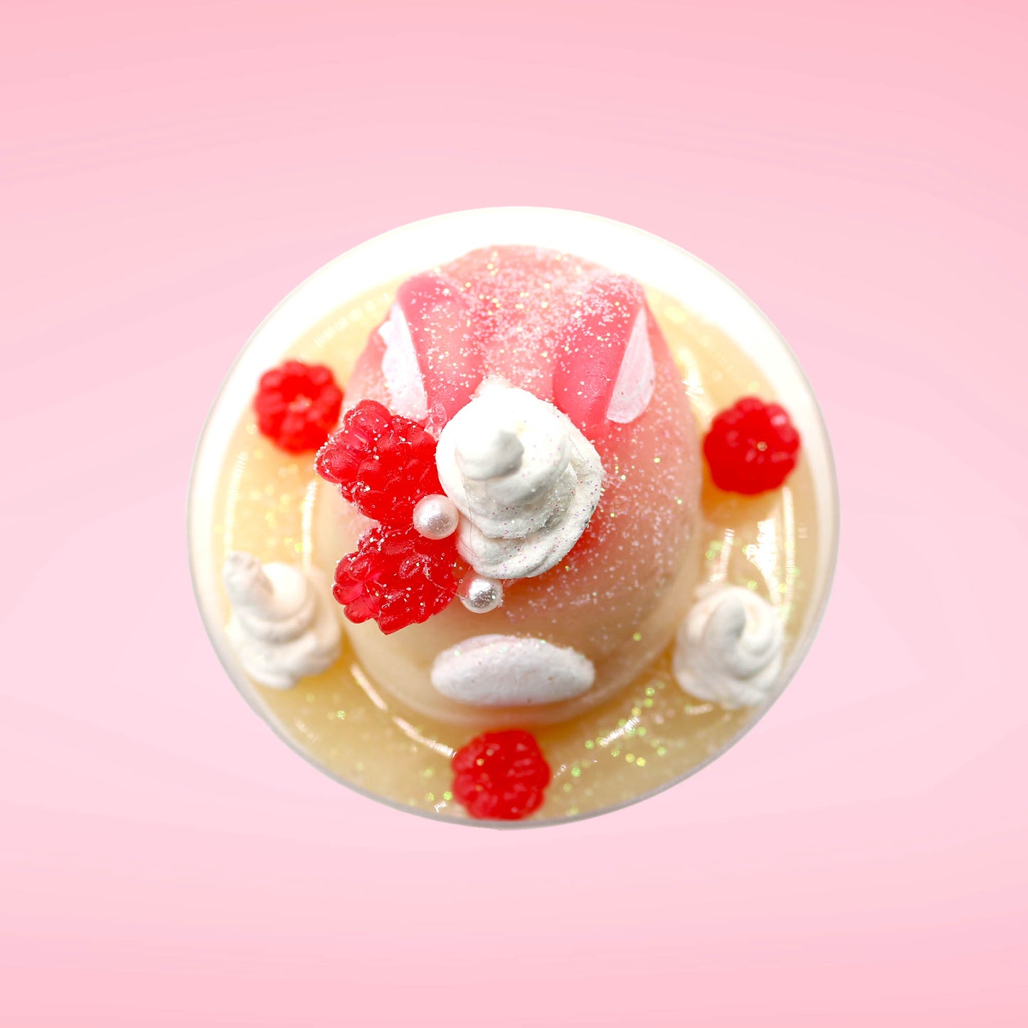 Cute kawaii bunny raspberry cheesecake white ice cream with raspberries and whipped cream swirls in the dish. The bunny has two raspberry on the back near the swirl of whipped cream and covered with white glitter. This view is from the top.