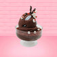Cute kawaii bunny rocky on the rocks ice cream brown sundae with marshmallows and brown bits in the dish. The marshmallows on the top of the ice cream have red berries as well as two swirls of solid chocolate that stick up and a swirl of whipped cream is on the back. There are two chocolate balls and one red ball on between the ears of the ice cream bunny. This view is from the side.