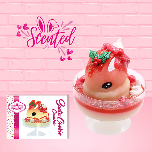 Cute kawaii bunny Santa Cookie Crumble white ice cream sundae with red glaze, glitter, red berries and whipped swirls in the dish. The bunny has red berries and green leaves on top with red translucent glaze near the whipped cream swirl. The front of the character card is shown with the word scented.