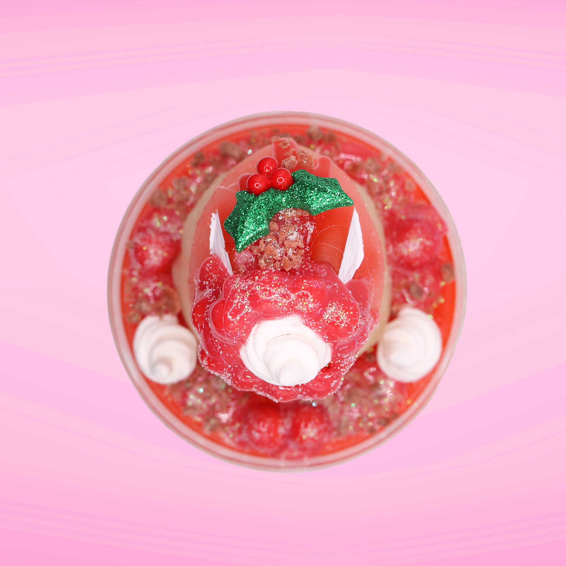 Cute kawaii bunny Santa Cookie Crumble white ice cream sundae with red glaze, glitter, red berries and whipped swirls in the dish. The bunny has red berries and green leaves on top with red translucent glaze near the whipped cream swirl. This view is from the top.