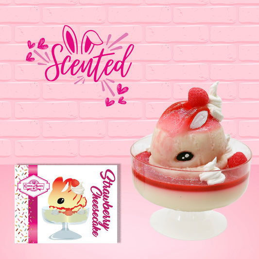 Cute kawaii bunny strawberry cheesecake white ice cream with red glaze, strawberries, and whipped cream swirls in the dish. The bunny has a strawberry on top between the ears, with a swirl of whipped cream on the back. The character card front which has the digital artwork of the ice cream and the word scented is also shown.