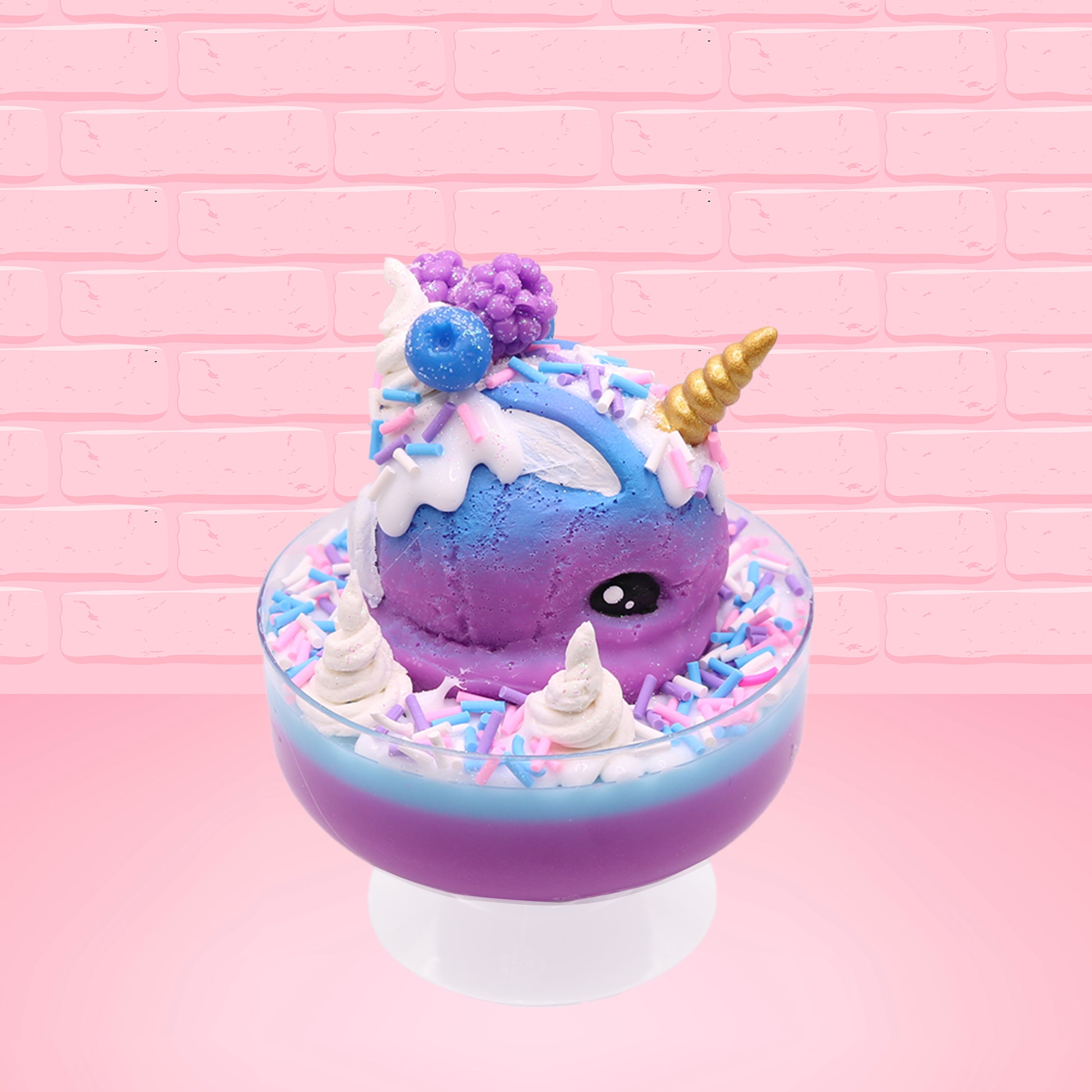 Cute kawaii unicorn bunny ice cream Sugar Berry Twilight sundae with whipped cream swirls, pink, blue, and white sprinkles in the dish. The unicorn bunny is purple and blue on top with blue berries and light purple raspberries, with a whipped cream swirl. This view is from the side.