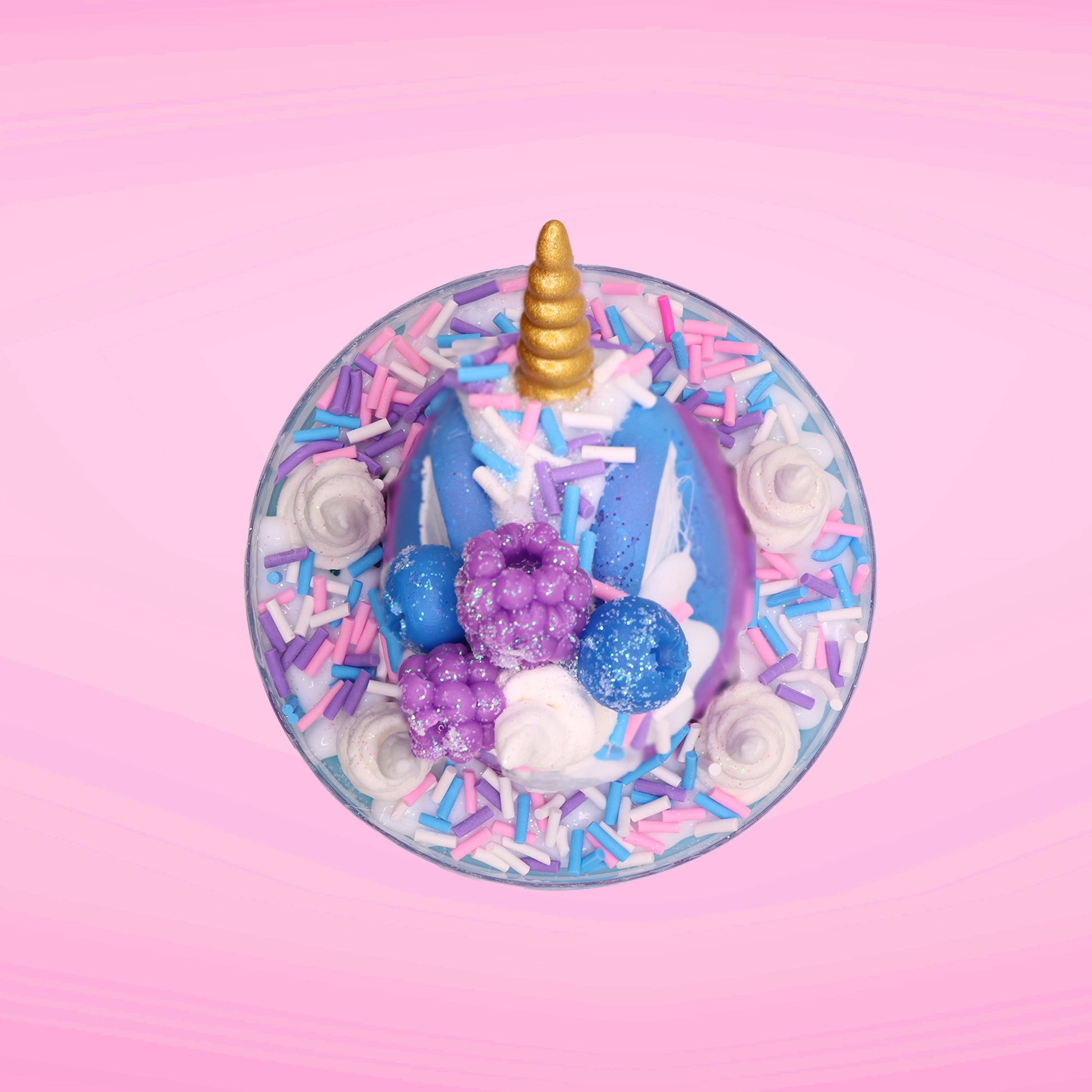 Cute kawaii unicorn bunny ice cream Sugar Berry Twilight sundae with whipped cream swirls, pink, blue, and white sprinkles in the dish. The unicorn bunny is purple and blue on top with blue berries and light purple raspberries, with a whipped cream swirl. This view is from the top.