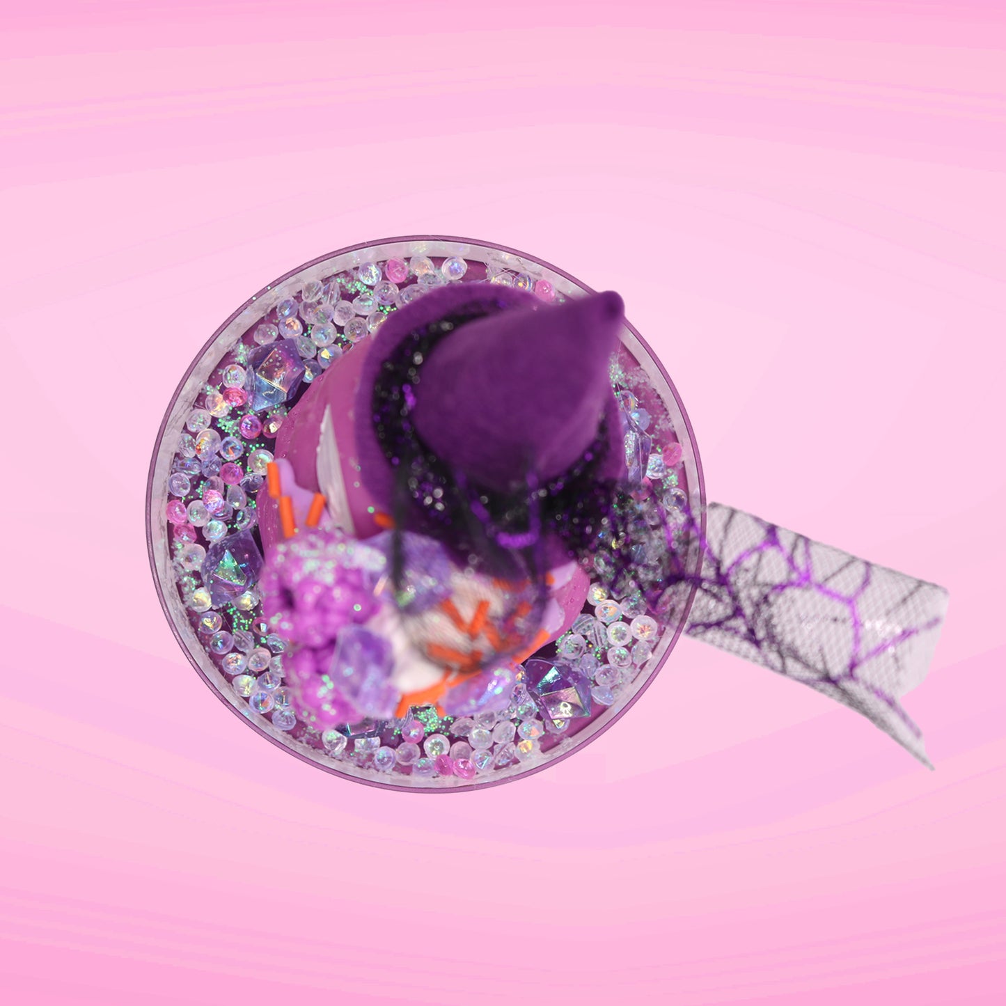 Cute kawaii witch bunny pink ice cream sundae with purple tall hat with translucent black layer covered with pink and purple crystals in the dish. The bunny has light purple raspberries near the swirl of whipped cream, and orange sprinkles in the light purple drippings. This view is from the top.