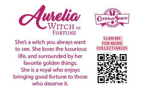 Cute kawaii witch bunny character card back, which reads: Aurelia Witch of Fortune, She’s a witch you always want to see. She loves the luxurious life, and surrounded by her favorite golden things. She is a royal who enjoys brining good fortune to those who deserve it. A QR code is available to be scanned for more collectibles as well as the cotton tails logo.