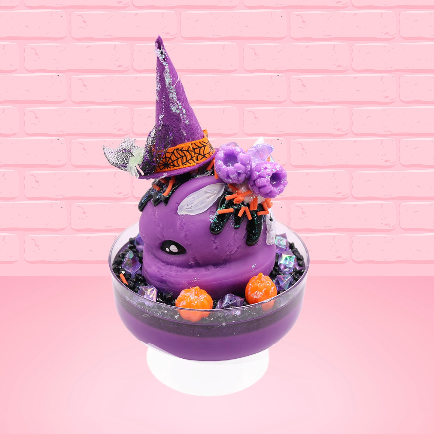 Cute kawaii witch bunny Blair purple ice cream with purple crystals and pumpkins on top of a layer of glittery black translucent layer. The bunny has a purple witch’s hat, with purple raspberries and a whipped cream swirl on top, with black glittery glaze and orange sprinkles. This view is from the other side.