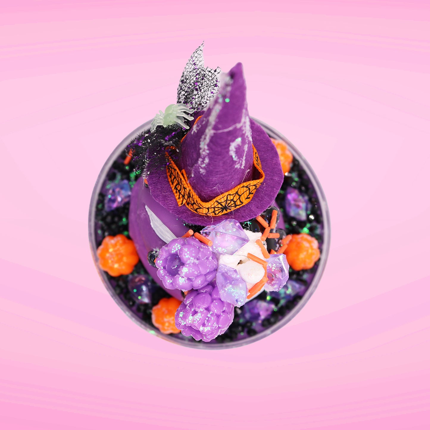 Cute kawaii witch bunny Blair purple ice cream with purple crystals and pumpkins on top of a layer of glittery black translucent layer. The bunny has a purple witch’s hat, with purple raspberries and a whipped cream swirl on top, with black glittery glaze and orange sprinkles. This view is from the top.