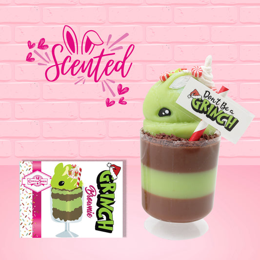 Cute kawaii bunny green Grinch Brownie tall sundae with brown sprinkles in the cup as well as a sign that reads don’t be a grinch. The ice cream bunny has peppermint candies, green and white sprinkles as well as a swirl of whipped cream on top.  The front of the character card is shown and the word scented. 