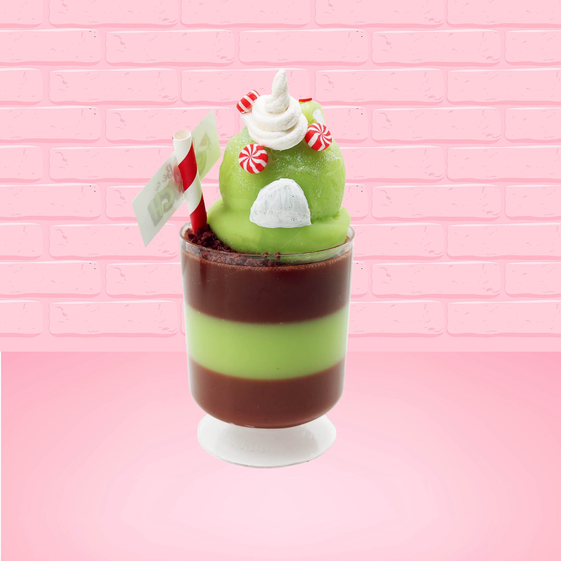 Cute kawaii bunny green Grinch Brownie tall sundae with brown sprinkles in the cup as well as a sign that reads don’t be a grinch.  The ice cream bunny has peppermint candies, green and white sprinkles as well as a swirl of whipped cream on top.  This view is from the back.
