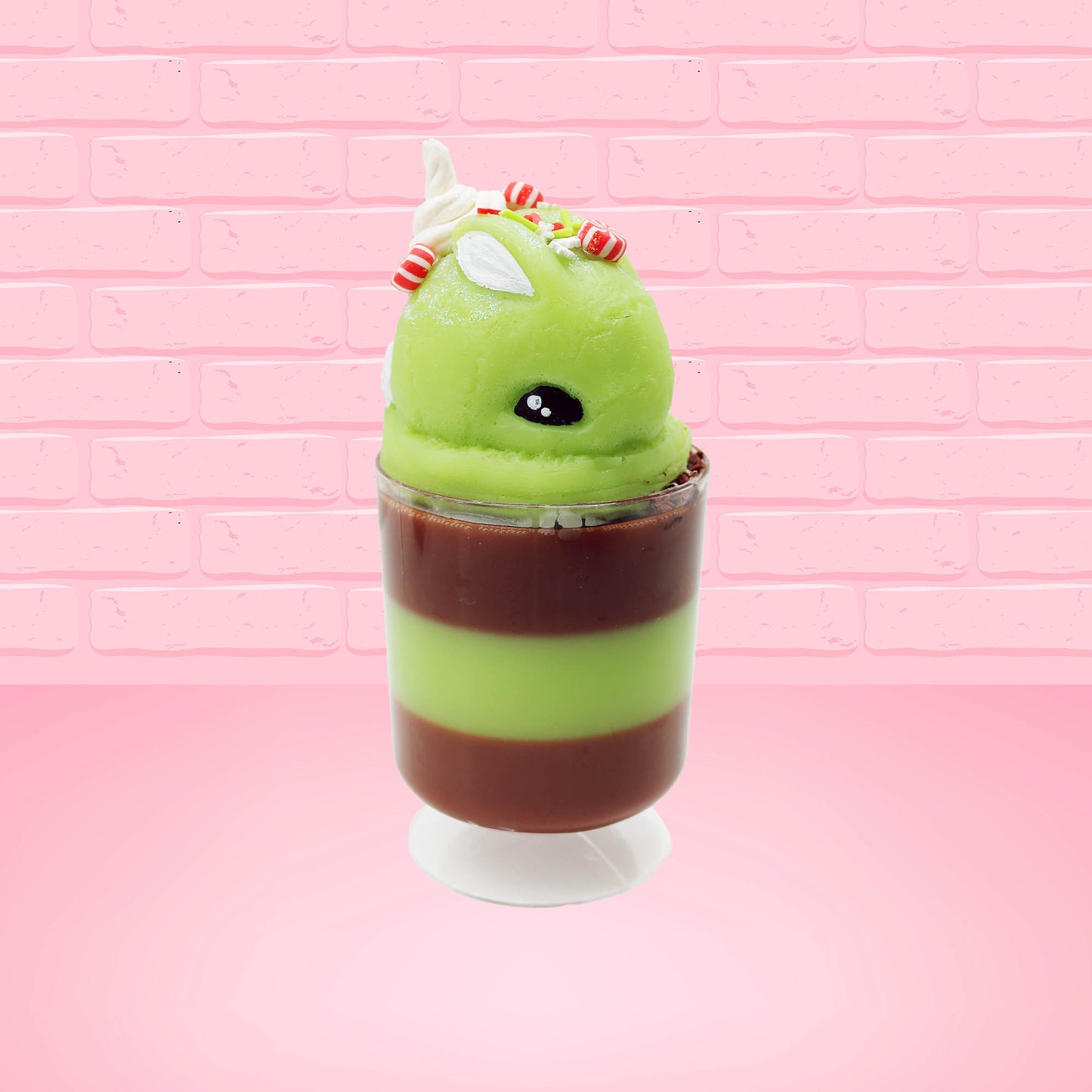 Cute kawaii bunny green Grinch Brownie tall sundae with brown sprinkles in the cup as well as a sign that reads don’t be a grinch.  The ice cream bunny has peppermint candies, green and white sprinkles as well as a swirl of whipped cream on top.  This view is from the front at an angle.