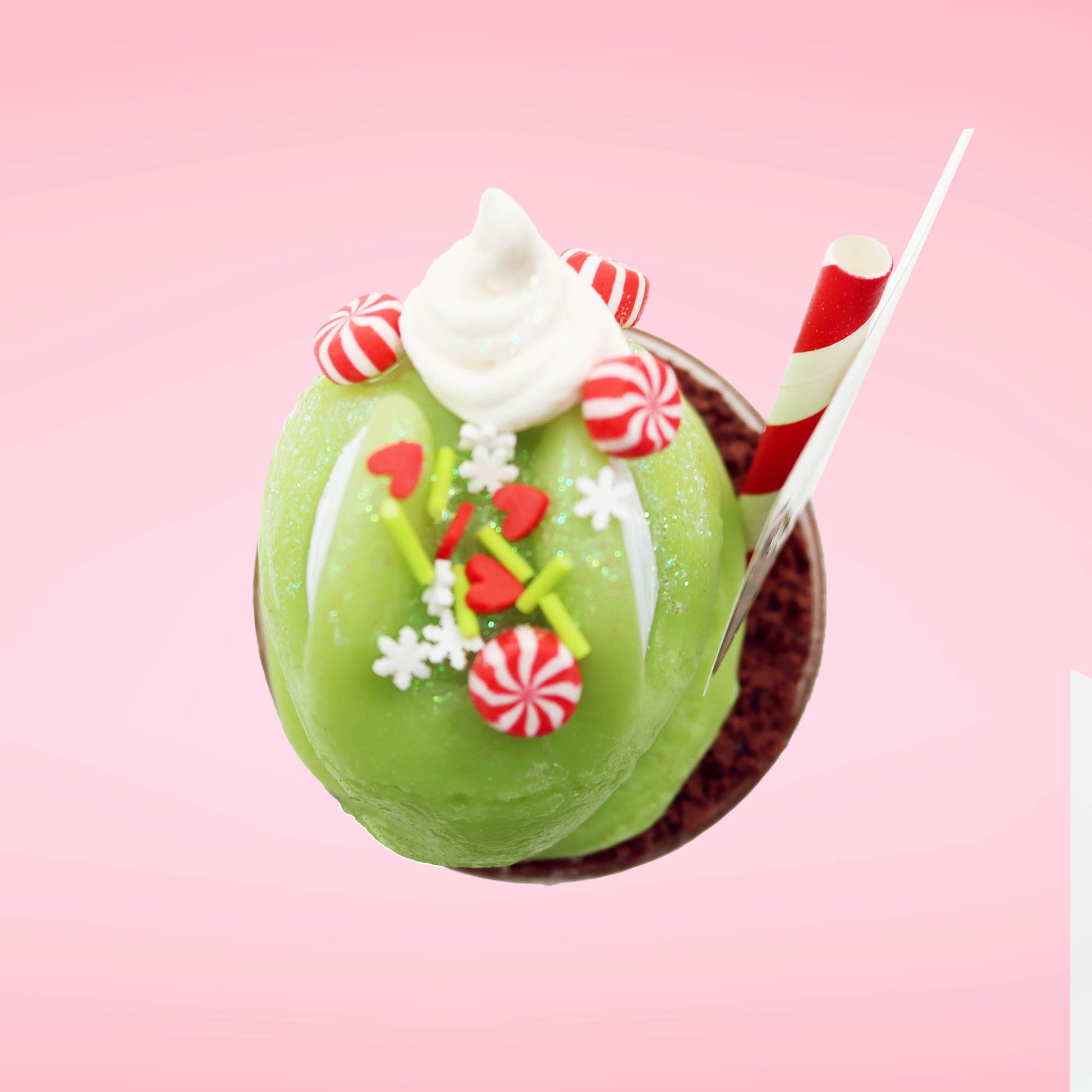 Cute kawaii bunny green Grinch Brownie tall sundae with brown sprinkles in the cup as well as a sign that reads don’t be a grinch.  The ice cream bunny has peppermint candies, green and white sprinkles as well as a swirl of whipped cream on top. This view is from the top. 