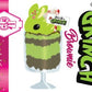 The front of the character card of the Grinch Brownie is shown with the digital artwork. The artwork shows tall sundae with brown sprinkles in the cup as well as a sign that reads don’t be a grinch.  The ice cream bunny has peppermint candies, green and white sprinkles as well as a swirl of whipped cream on top.