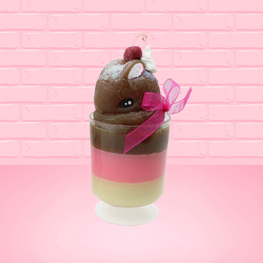 Cute Kawaii bunny tall Neapolitan three layered ice cream sundae with a cherry and swirl of whipped cream on top.  The top of the bunny is covered with white glitter, and has a pink bow.  This view is from the front at an angle.