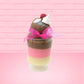 Cute Kawaii bunny tall Neapolitan three layered ice cream sundae with a cherry and swirl of whipped cream on top.  The top of the bunny is covered with white glitter, and has a pink bow.  This view is from the side.