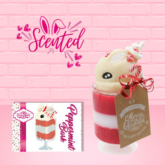 Cute kawaii bunny Peppermint Bark white ice cream tall sundae that has red and white layers in the dish and a peppermint candy cane holding a brown and white tag. The tag reads We wish you a merry Christmas and a happy new year, and the bunny has bits of peppermint candy on top as well as swirl of whipped cream.  The front of the character card is shown as well as the word scented.