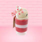 Cute kawaii bunny Peppermint Bark white ice cream tall sundae that has red and white layers in the dish and a peppermint candy cane holding a brown and white tag. The tag reads We wish you a merry Christmas and a happy new year, and the bunny has bits of peppermint candy on top as well as swirl of whipped cream. This view is from the other side.