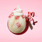 Cute kawaii bunny Peppermint Bark white ice cream tall sundae that has red and white layers in the dish and a peppermint candy cane holding a brown and white tag. The tag reads We wish you a merry Christmas and a happy new year, and the bunny has bits of peppermint candy on top as well as swirl of whipped cream. This view is from the top.