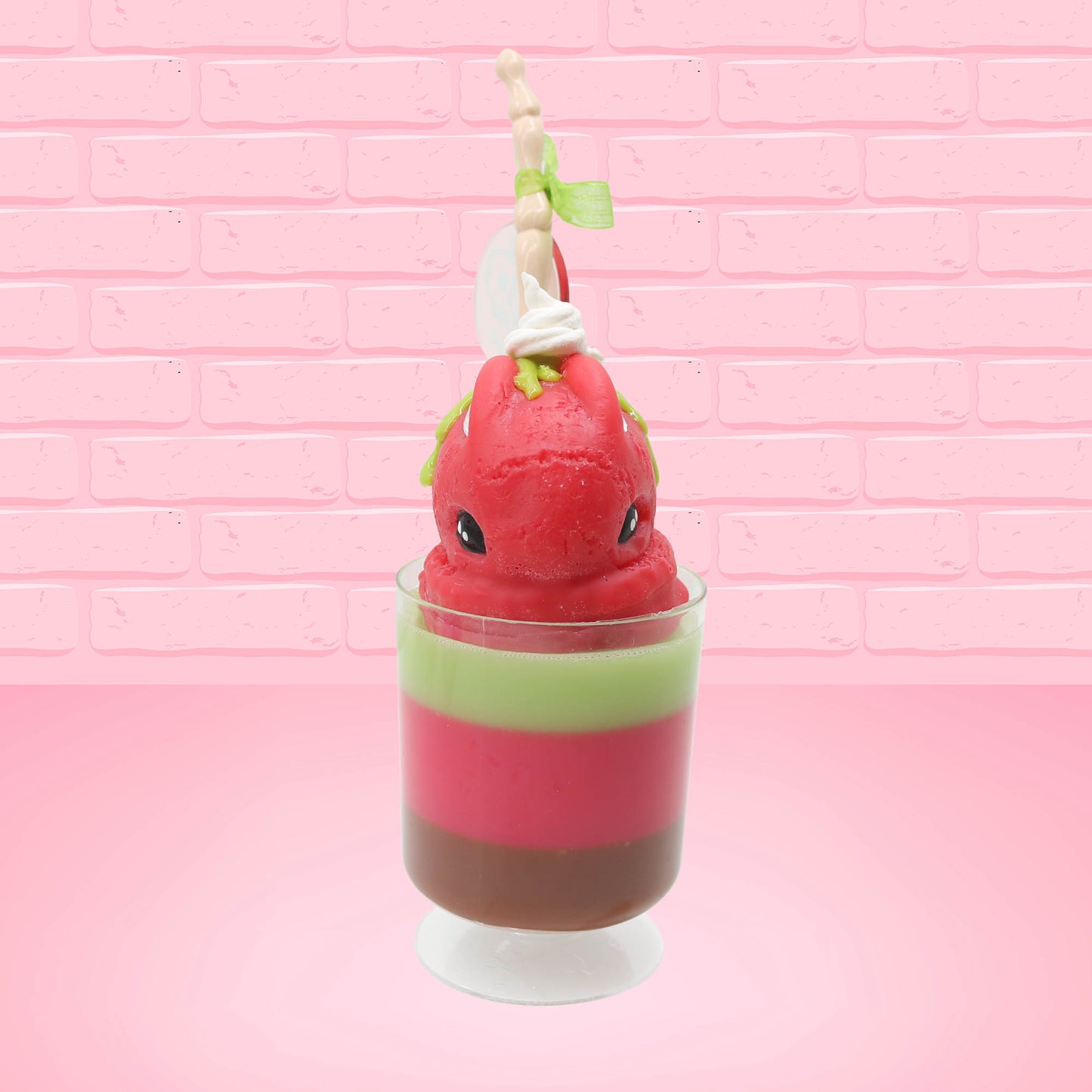 Cute kawaii bunny tall red green and brown ice cream sundae with green glaze and a swirl of whipped cream up top. In the top of the bunny is a bony finger with the poison apple acrylic keychain attached to it. This view is from the front.