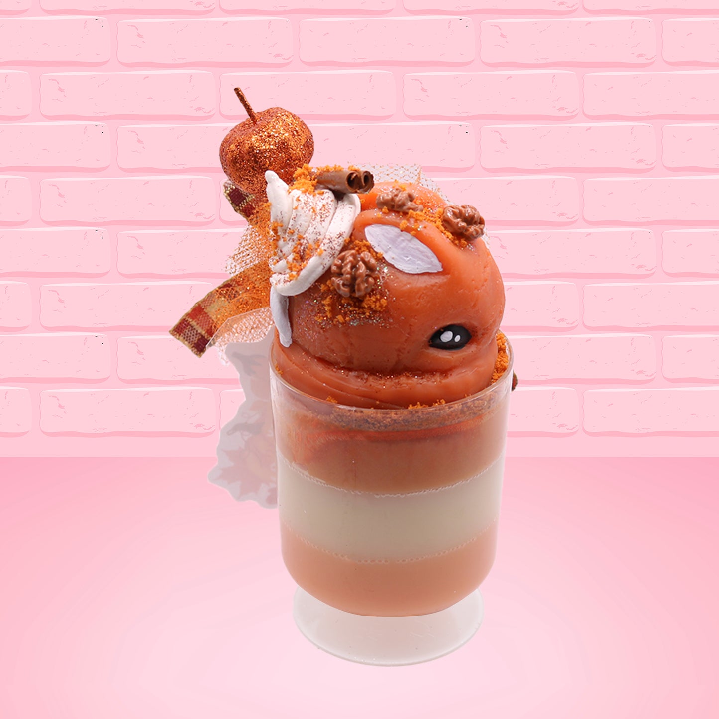 Cute kawaii bunny orange ice cream tall sundae that has orange tulle, a fall colored bow with a pumpkin in the middle, brown pecan halves, cinnamon twig on the whipped cream on top, and a glittery pumpkin stuck into the dish. This view is from the side.