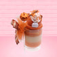 Cute kawaii bunny orange ice cream tall sundae that has orange tulle, a fall colored bow with a pumpkin in the middle, brown pecan halves, cinnamon twig on the whipped cream on top, and a glittery pumpkin stuck into the dish. This view is from the back.