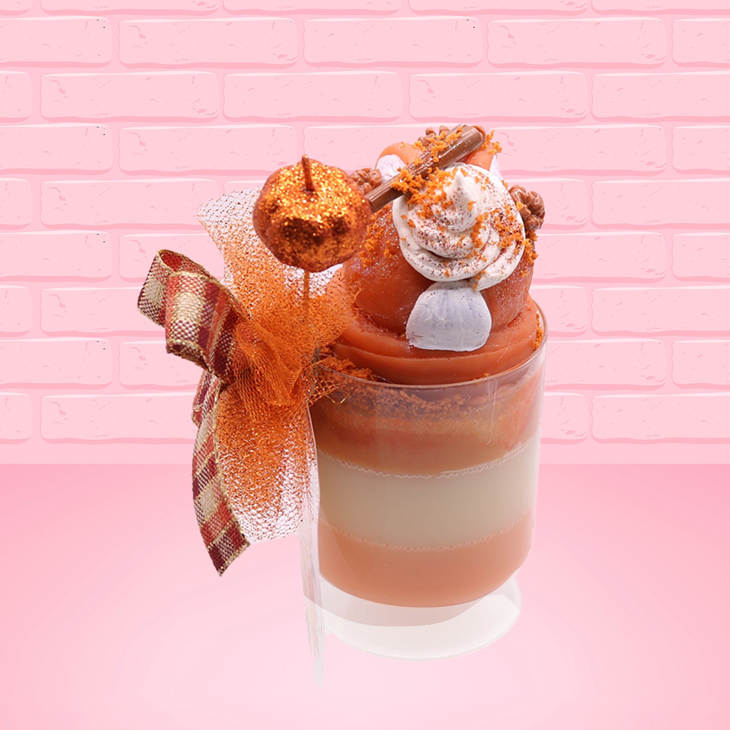 Cute kawaii bunny orange ice cream tall sundae that has orange tulle, a fall colored bow with a pumpkin in the middle, brown pecan halves, cinnamon twig on the whipped cream on top, and a glittery pumpkin stuck into the dish. This view is from the back.