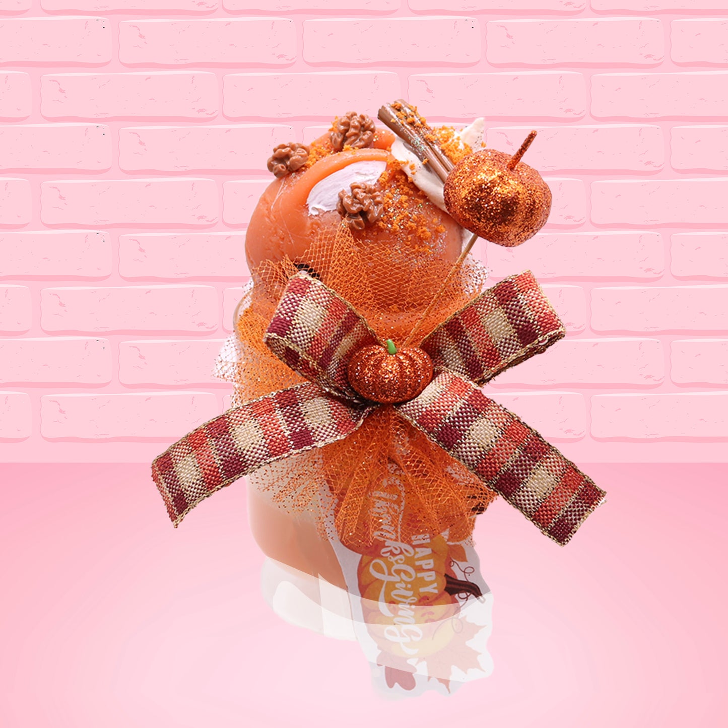Cute kawaii bunny orange ice cream tall sundae that has orange tulle, a fall colored bow with a pumpkin in the middle, brown pecan halves, cinnamon twig on the whipped cream on top, and a glittery pumpkin stuck into the dish. This view is from the top.