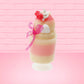 Cute kawaii bunny Raspberry Cheesecake white tall sundae with raspberries and a whipped cream swirl on top and a pink bow on the side. The bunny has glittery pink ears. This view is from the back.
