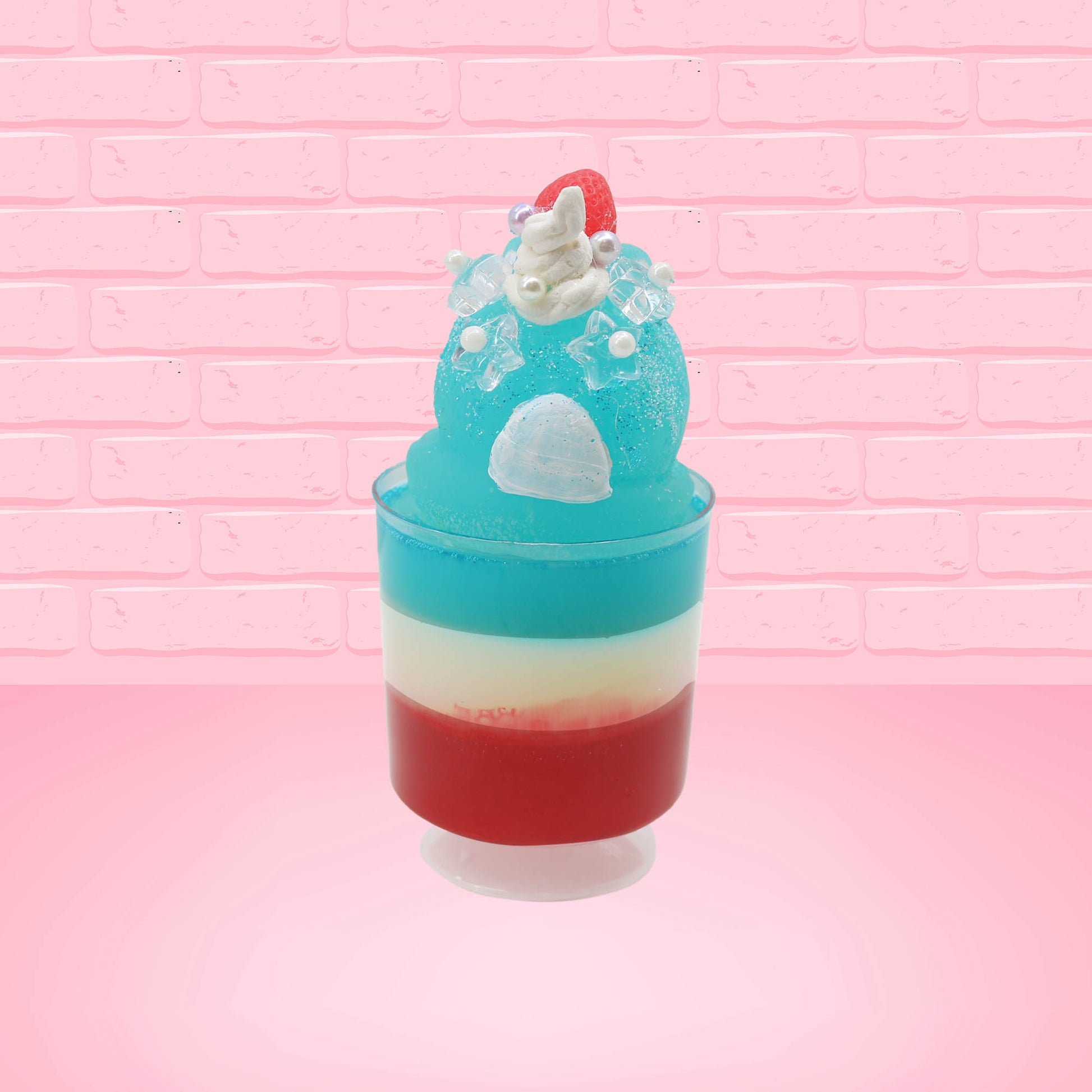 Cute kawaii bunny blue ice cream tall sundae that has red, white and blue layers in the dish and a strawberry on top near the whipped cream and pearls. The photo is taken from the back.